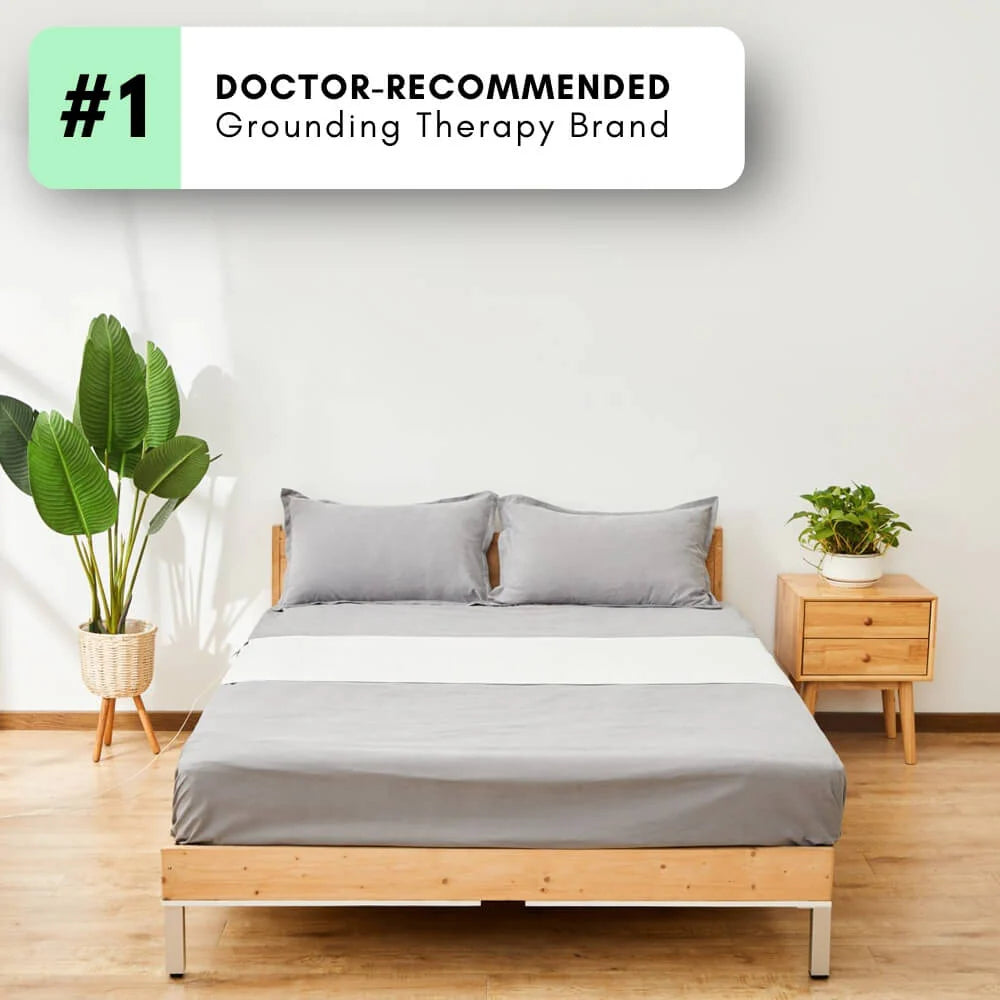 Bedroom with a wooden bed frame and gray bedding, featuring a 'Doctor-Recommended Grounding Therapy Brand' label.